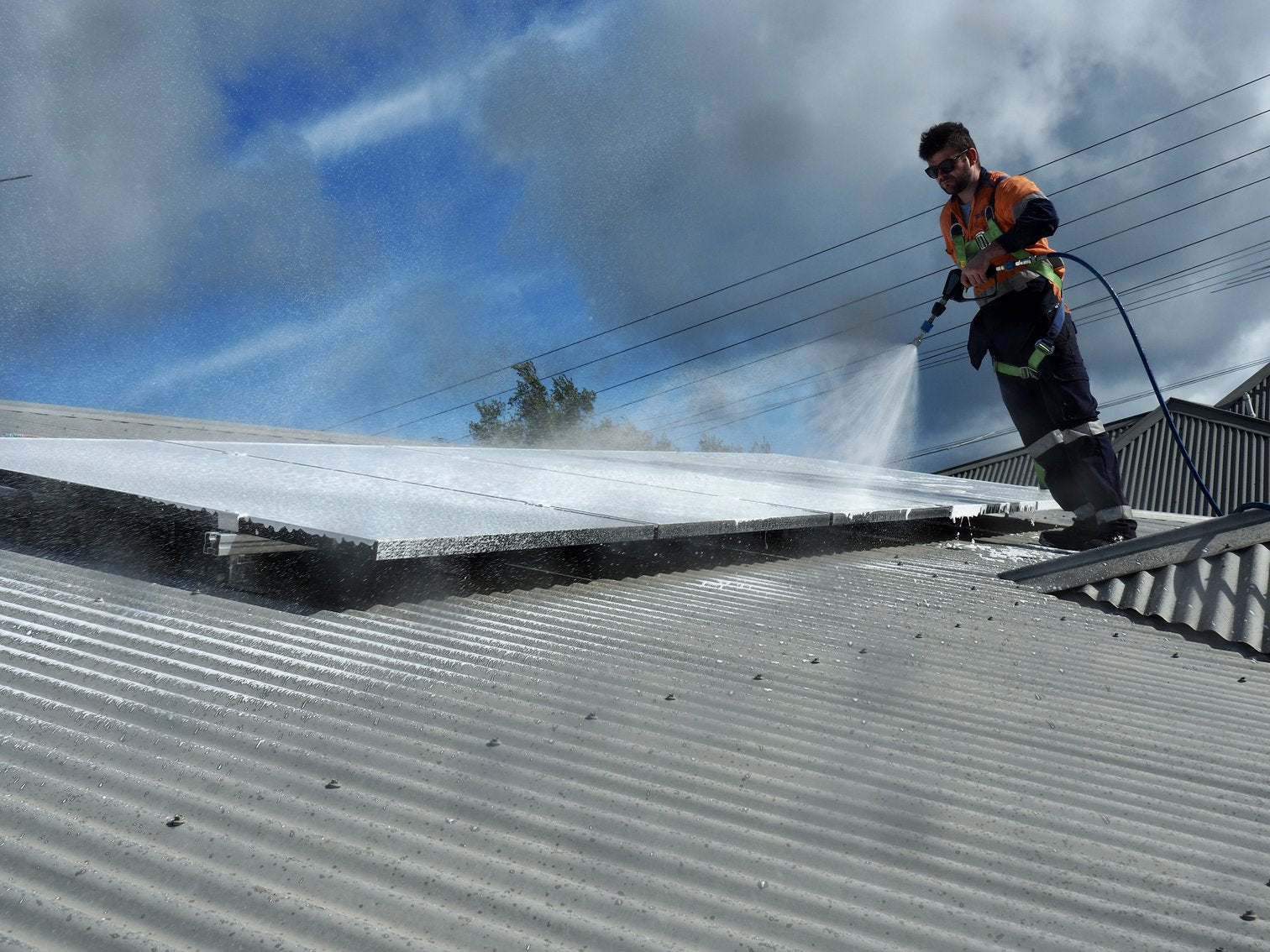 Technician Cleaning Solar Panels on Roof