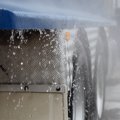 Truck wheels being rinsed with a pressure washer with water droplets.