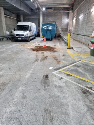 Van parked in a concrete garage with a oil spill on the ground