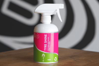 Lifestyle Shot of White Spray Bottle of "Tyre Shine" with Pink & Green Label with Logo