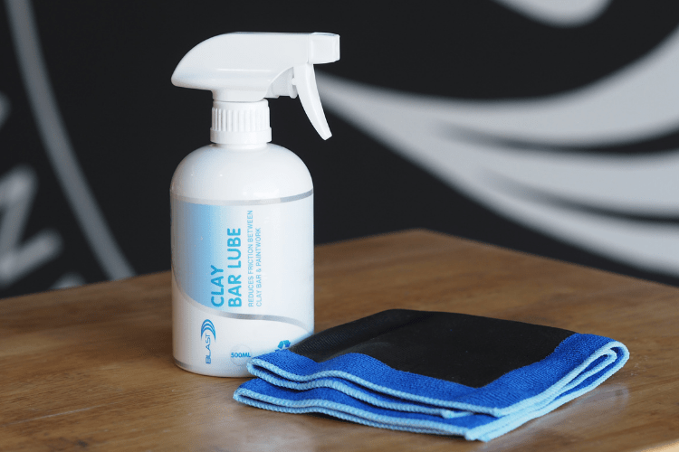 Lifestyle Shot of Spray Bottle of "Clay Bar Lube" and Clay Bar Cloth with Blue Trim