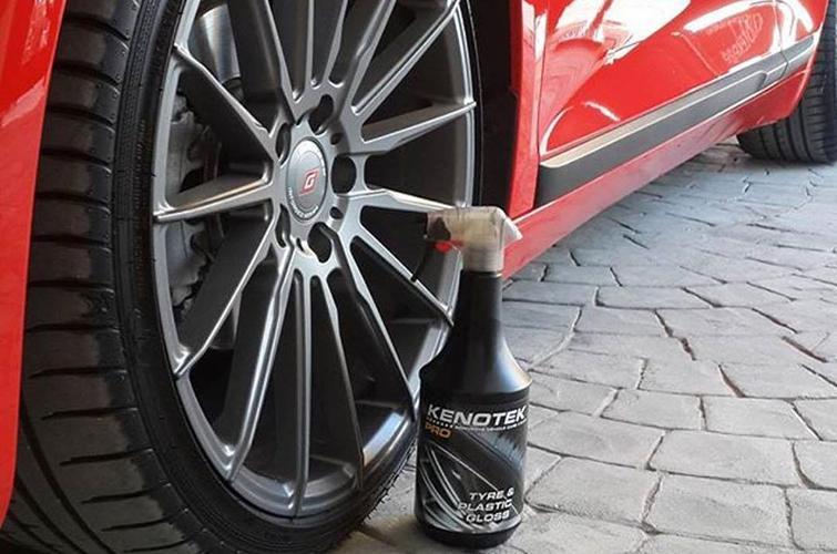 Kenotek 'Tyre & Plastic Gloss' Spray Bottle Sitting Next to A Wheel of a Red Car